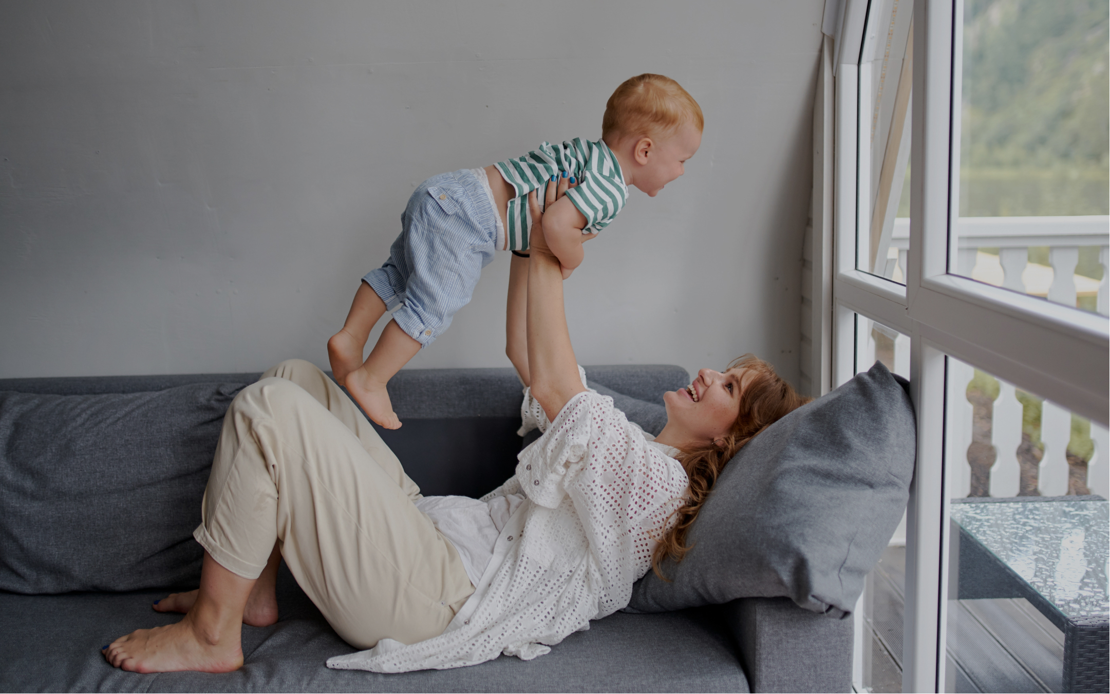 Mum laying on couch holding up baby