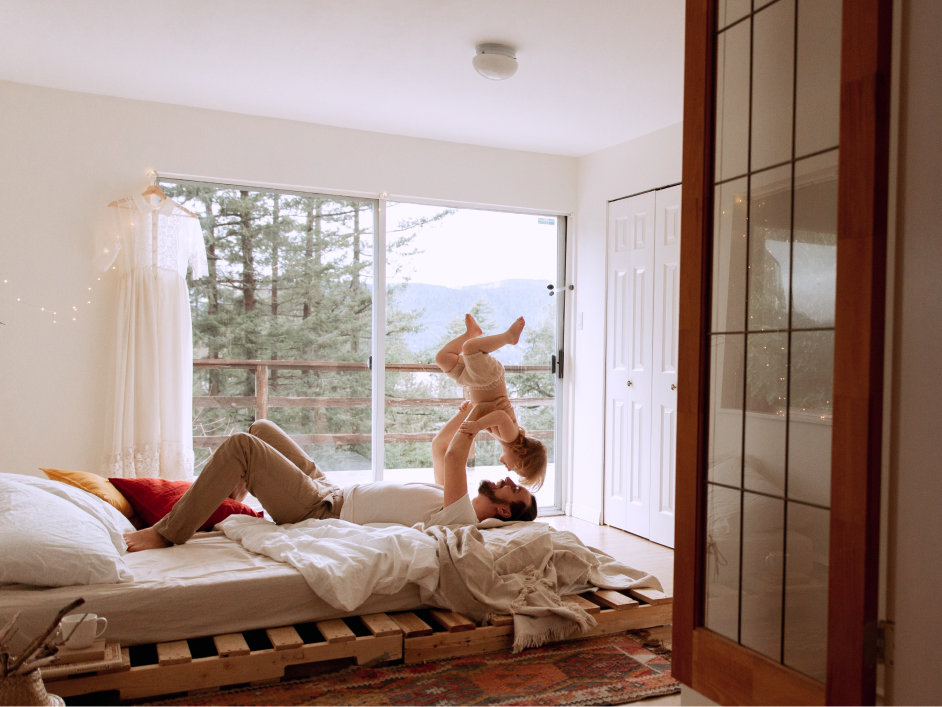 Man laying on bed, holding up baby