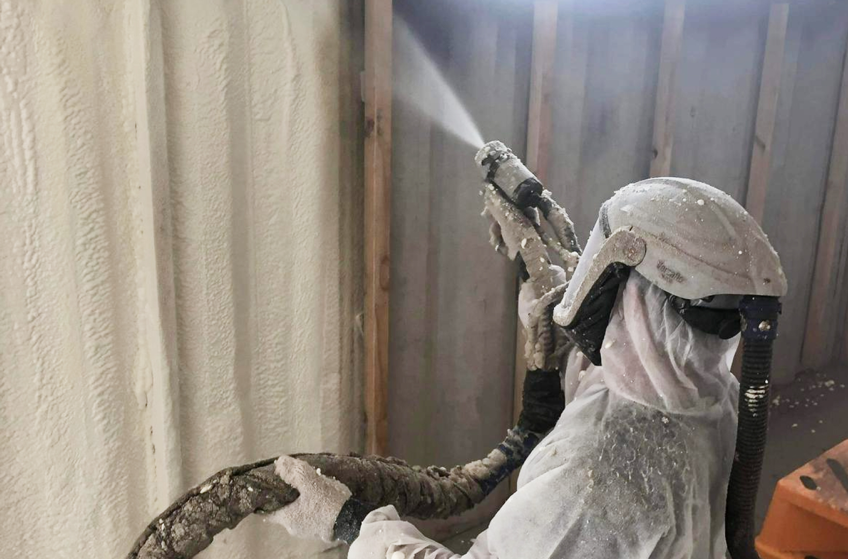 Person wearing PPE, spraying a wall
