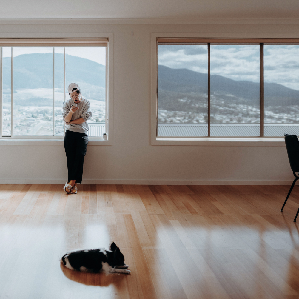 Woman leaning against windows at home with Hobart as a backdrop