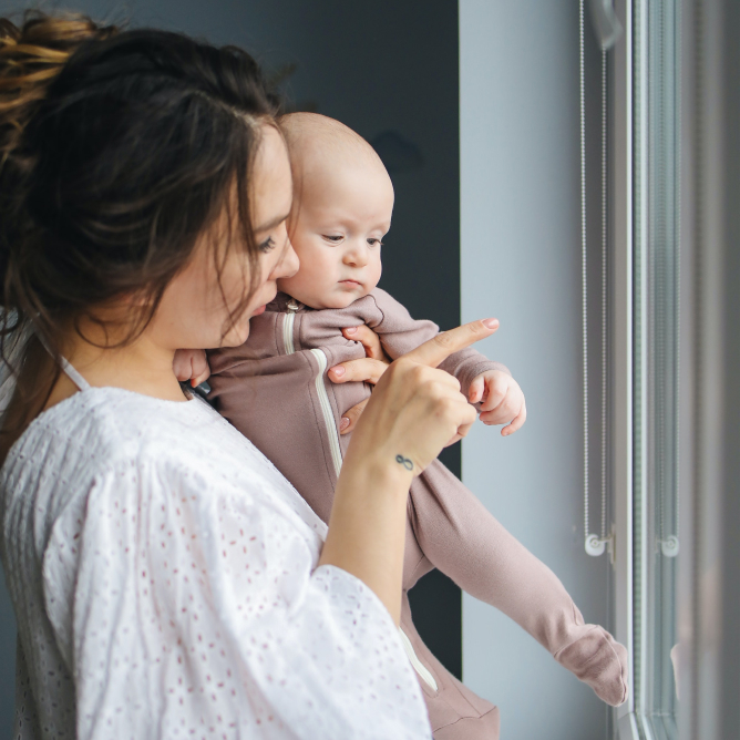 Woman holding baby looking out the window