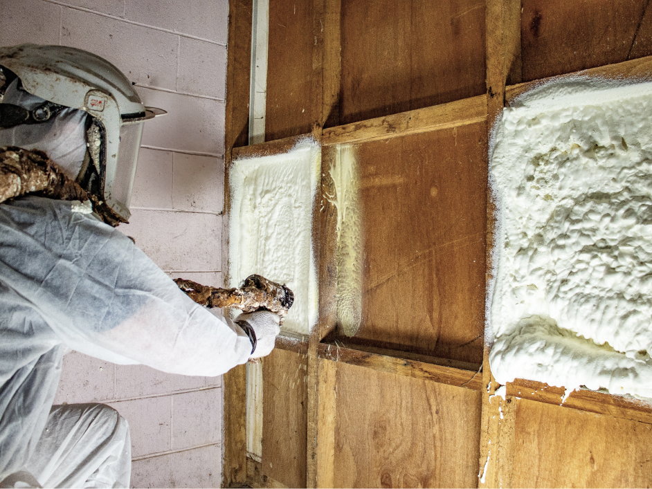 Man in PPE spraying wall